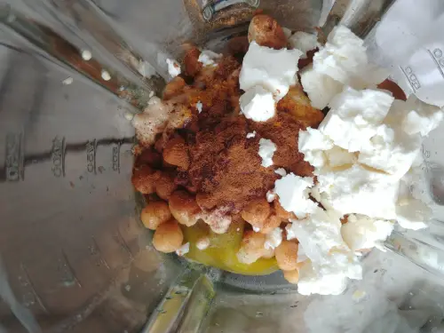 Vue des ingrédients dans le mixeur avec les épices, la feta et le poivron visibles. 
