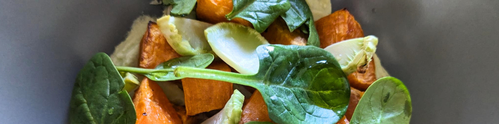 Assiette creuse avec des légumes : crème avocat, épinard, brocolis et patate douce coupé en cube.